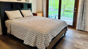 A bedroom with a bed, a nightstand, a window with a view of the outdoors, and three framed pictures on the wall. - Extra clean home-free parking & Wi-Fi/self-check-in (Champaign)