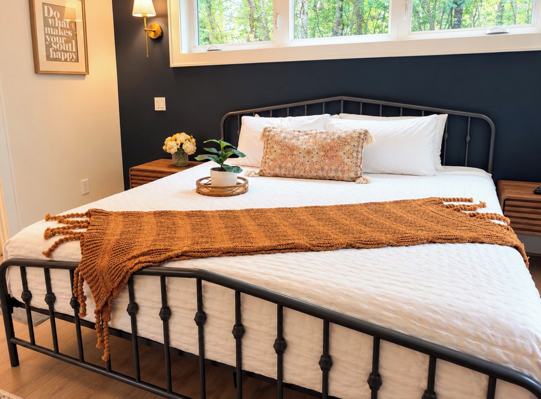 A bed with a white mattress, a brown knitted blanket, and a decorative pillow.