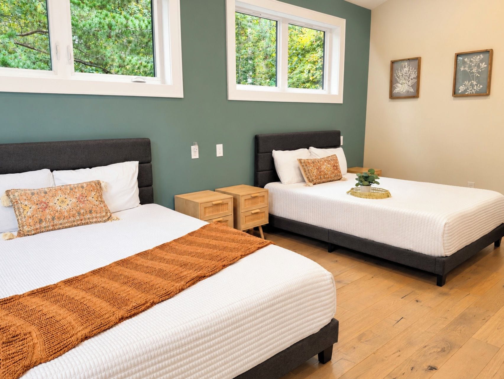 A bedroom with two beds, a window, and a nightstand.