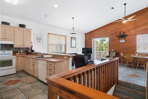 A spacious kitchen with wooden cabinets, a dishwasher, and a dining area with a wooden railing.