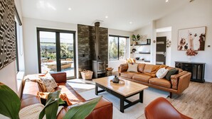 A spacious living room with a large sofa, a coffee table, and a fireplace. - Minaret Ridge - Family friendly (Wanaka)