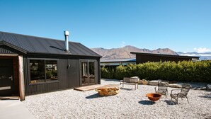 A modern building with a gravel patio, outdoor seating, and a mountain view. - Minaret Ridge - Family friendly (Wanaka)
