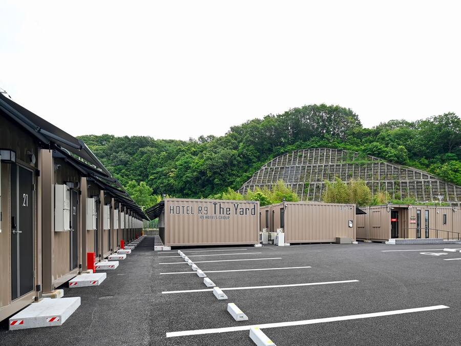 A row of hotel rooms with a view of a forested hillside.