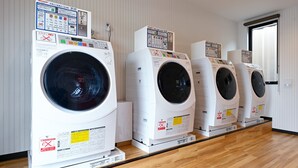 A row of white front-loading washing machines in a room with wooden flooring and white walls. - HOTEL R9 The Yard Kasai (Kasai)