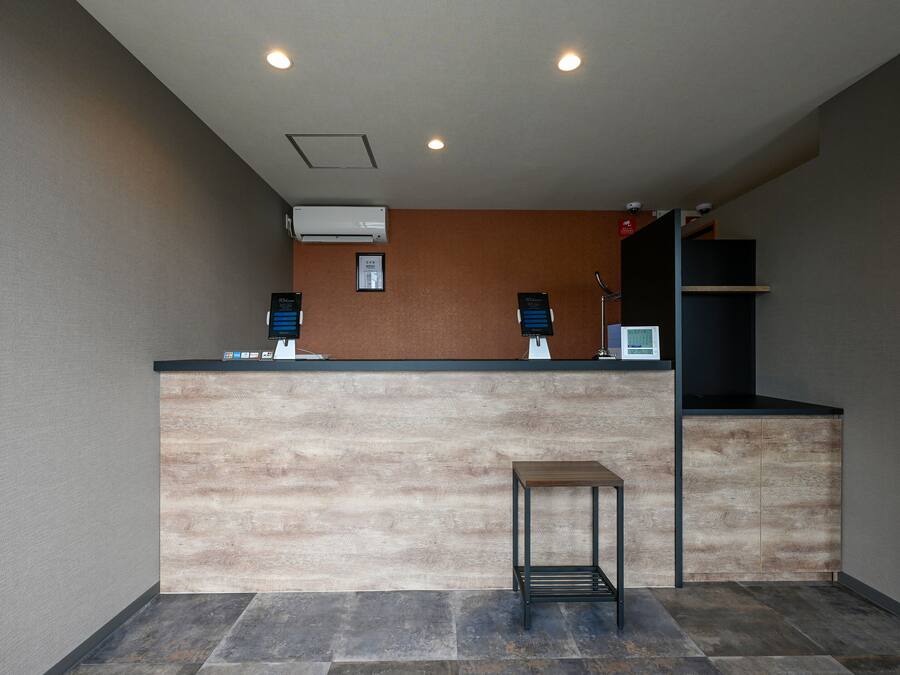 A reception area with a wooden reception desk, air conditioning unit, and a small table.