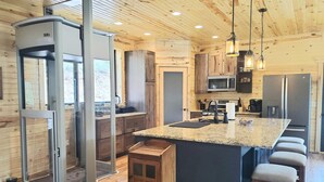 Una cocina moderna con armarios de madera, encimera de granito y una isla integrada con taburetes de bar.