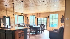 Una cocina amplia con una isla grande, piso de madera y un comedor con sillas y mesa.