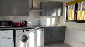 Een kleine keuken met grijze kastjes, een wasmachine en een vaatwasser.