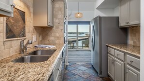 Una cucina moderna con piani in granito, elettrodomestici in acciaio inossidabile e vista su un balcone.