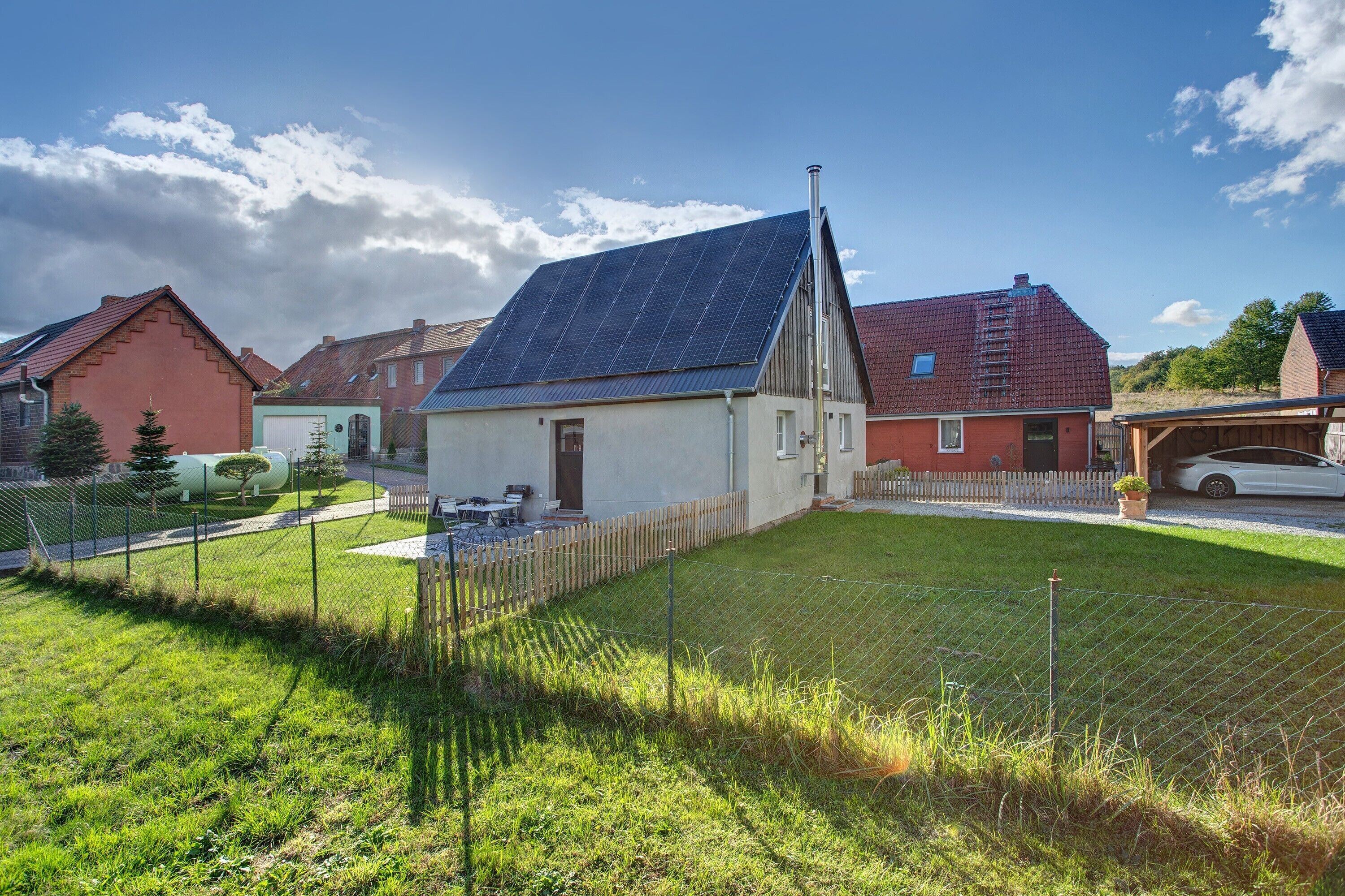 A residential area with houses, a fenced yard, and a solar panel on one house.
