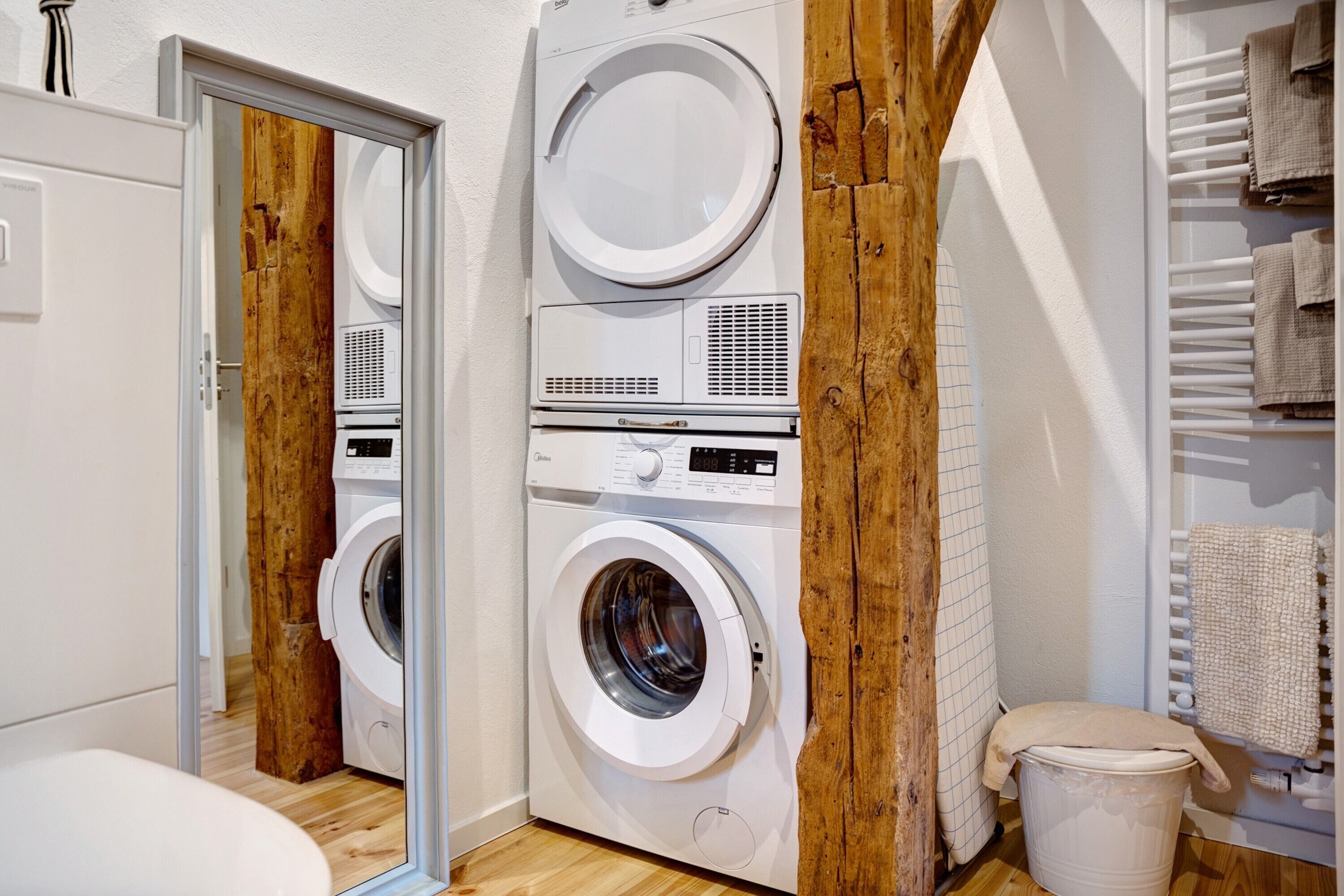 A laundry room with a washing machine, dryer, and a wooden beam structure.