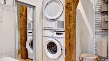 A laundry room with a washing machine, dryer, and a wooden beam structure.