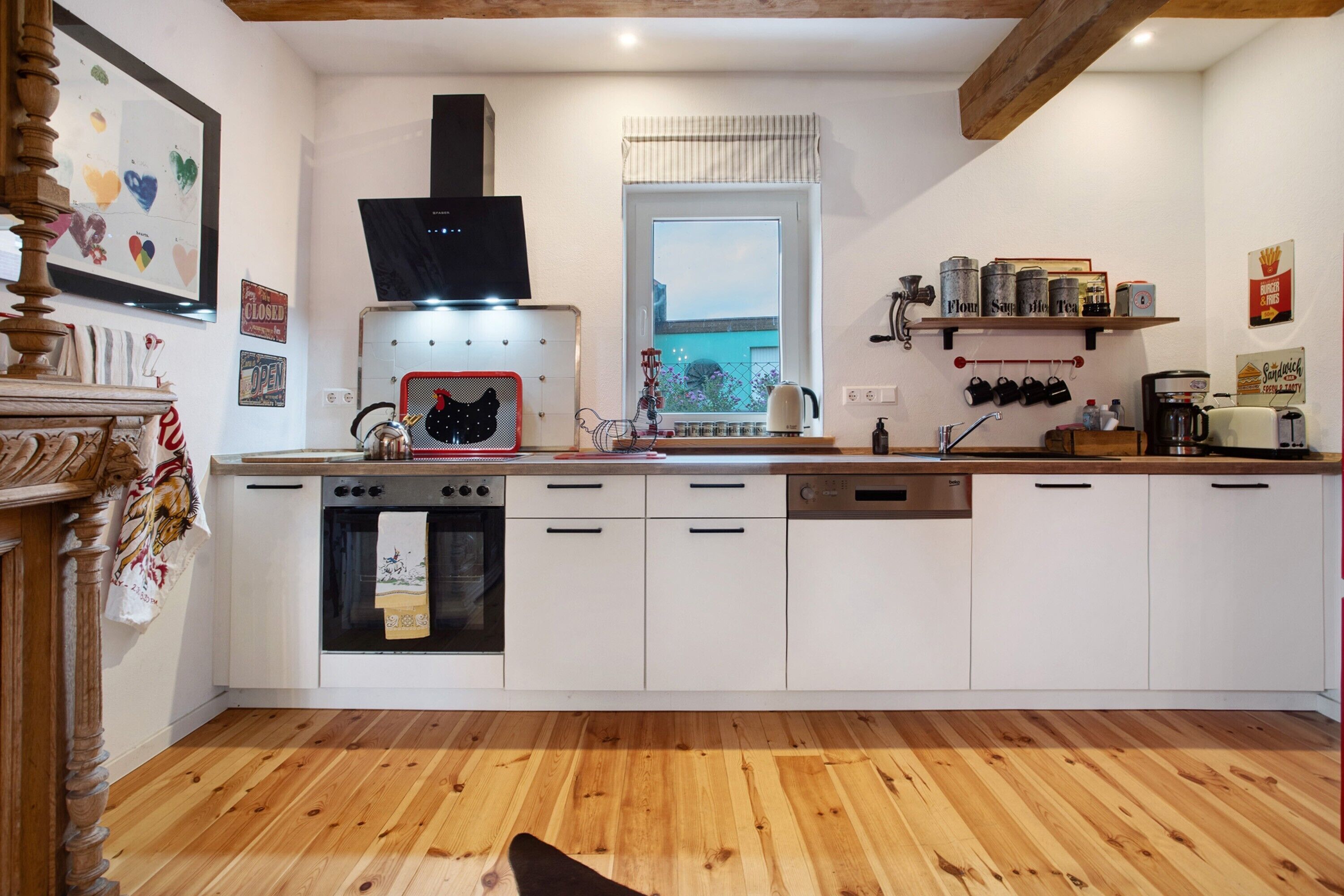 A modern kitchen with white cabinets, a built-in oven, and a window with a view.