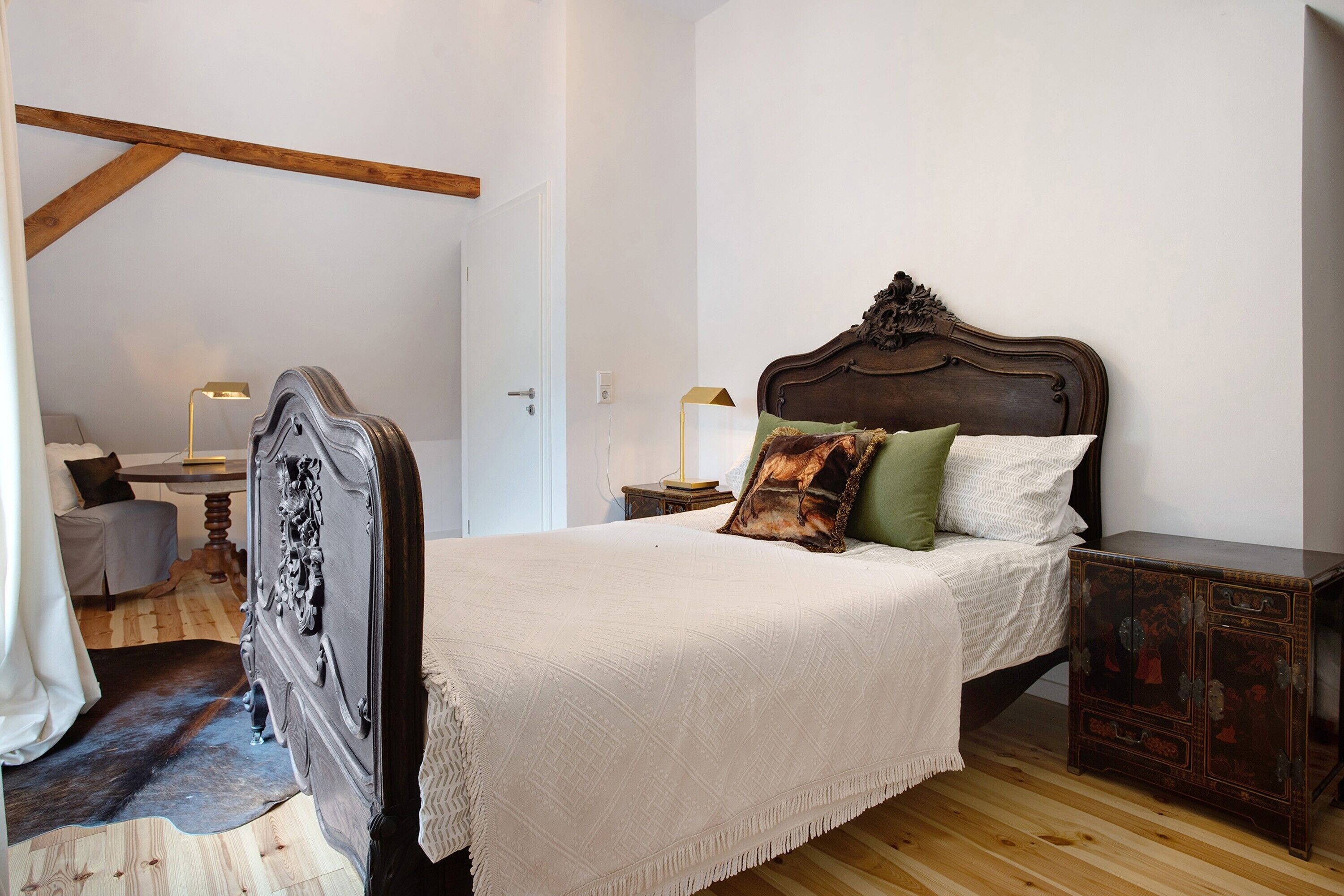 A bedroom with a wooden headboard, a white bedspread, and a small bedside table with a lamp.