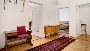 Une pièce avec un banc en bois, un tapis rouge, une table en bois et un porte-manteau suspendu.
