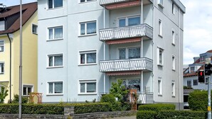 Un immeuble résidentiel à plusieurs étages, doté de balcons, d’une entrée bien visible et donnant sur la rue.