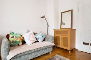 A room with a patterned sofa, a wooden cabinet, and a floor lamp.