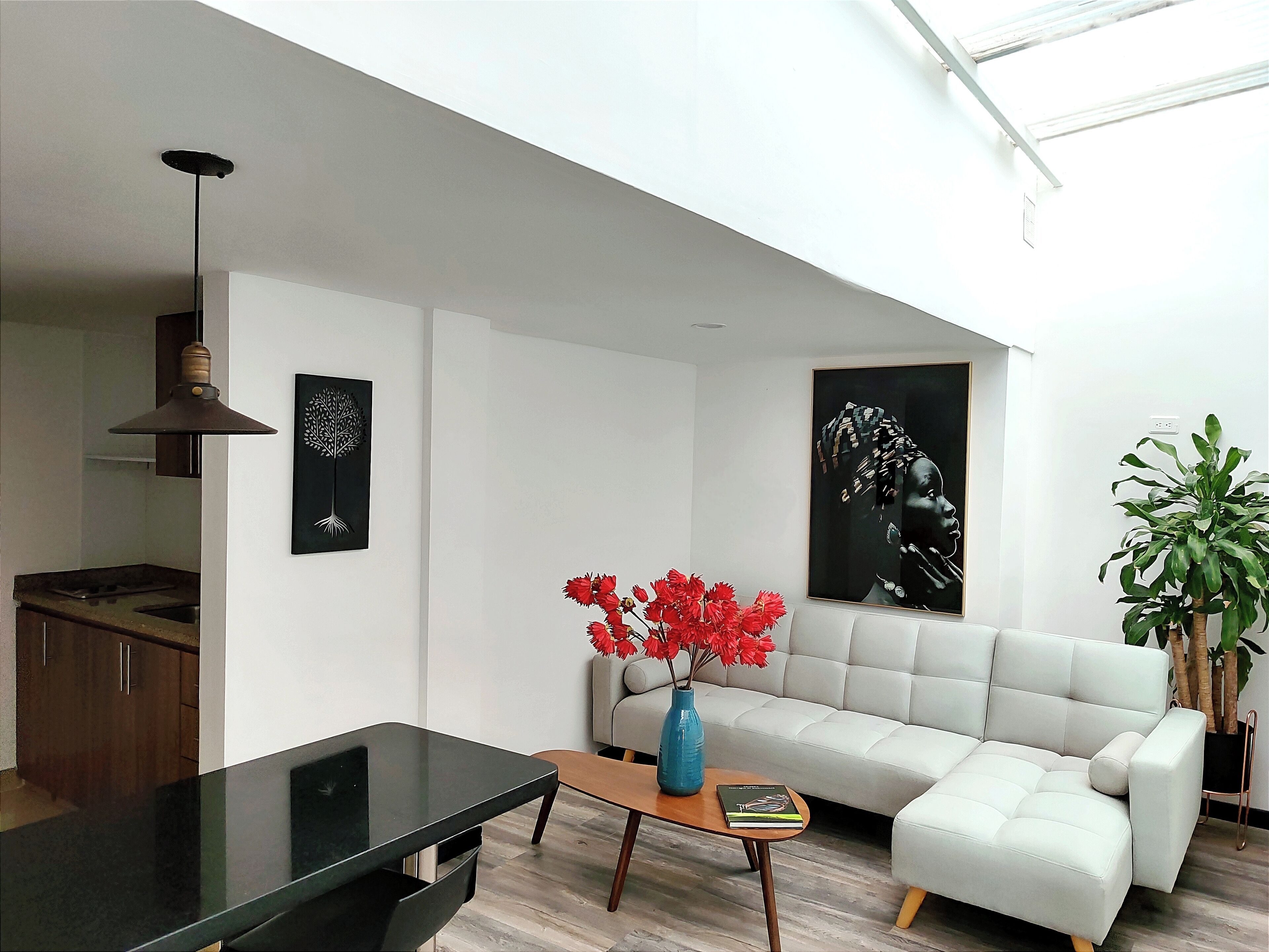 A modern living room with a sofa, a coffee table, a TV, and a dining area with a stove.