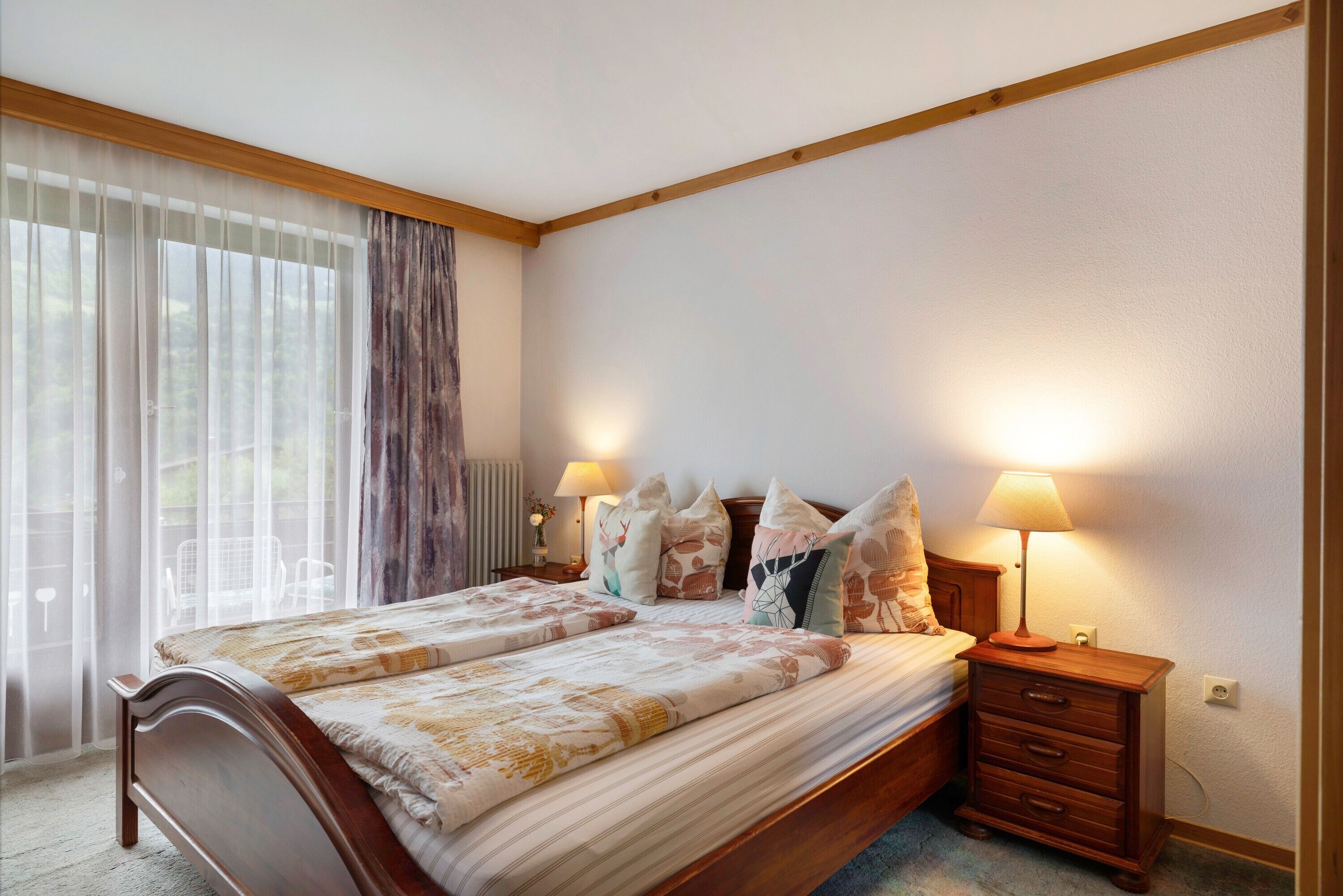 Une chambre à coucher avec un lit, des lampes de chevet, une table de chevet et une fenêtre avec des rideaux.