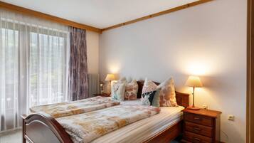 Une chambre à coucher avec un lit, des lampes de chevet, une table de chevet et une fenêtre avec des rideaux.