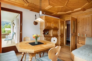 A wooden interior with a dining table, chairs, a vase with flowers, and wooden cabinets. - Apartment 'Jordis' with Mountain View, Private Terrace, garden and Wi-Fi (Vandans)