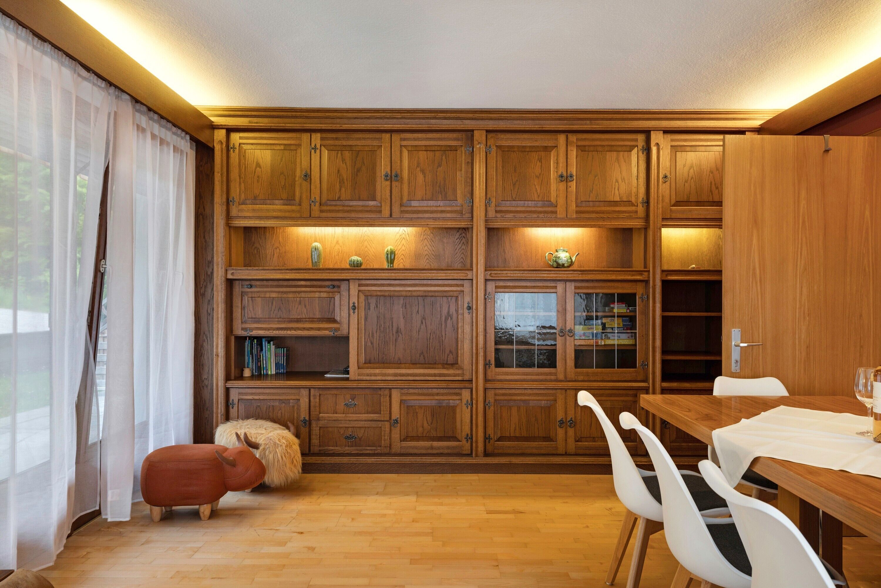 A wooden kitchen with built-in cabinets, a dining table with chairs, and a small decorative animal.