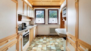 Eine kleine Küche mit Holzausstattung, integriertem Backofen, Spüle und einem Fenster mit Vorhängen.