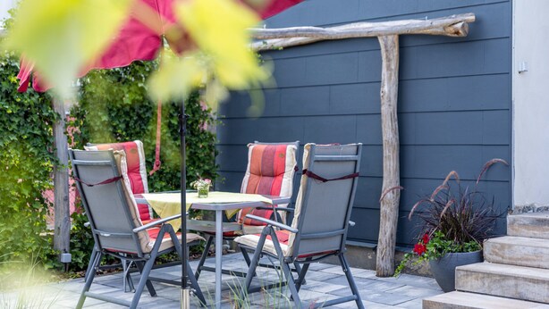 An outdoor patio with two chairs, a table, and a red umbrella. - Apartment 'Baumelt' with Private Terrace, Shared Garden and Wi-Fi (Hechingen)