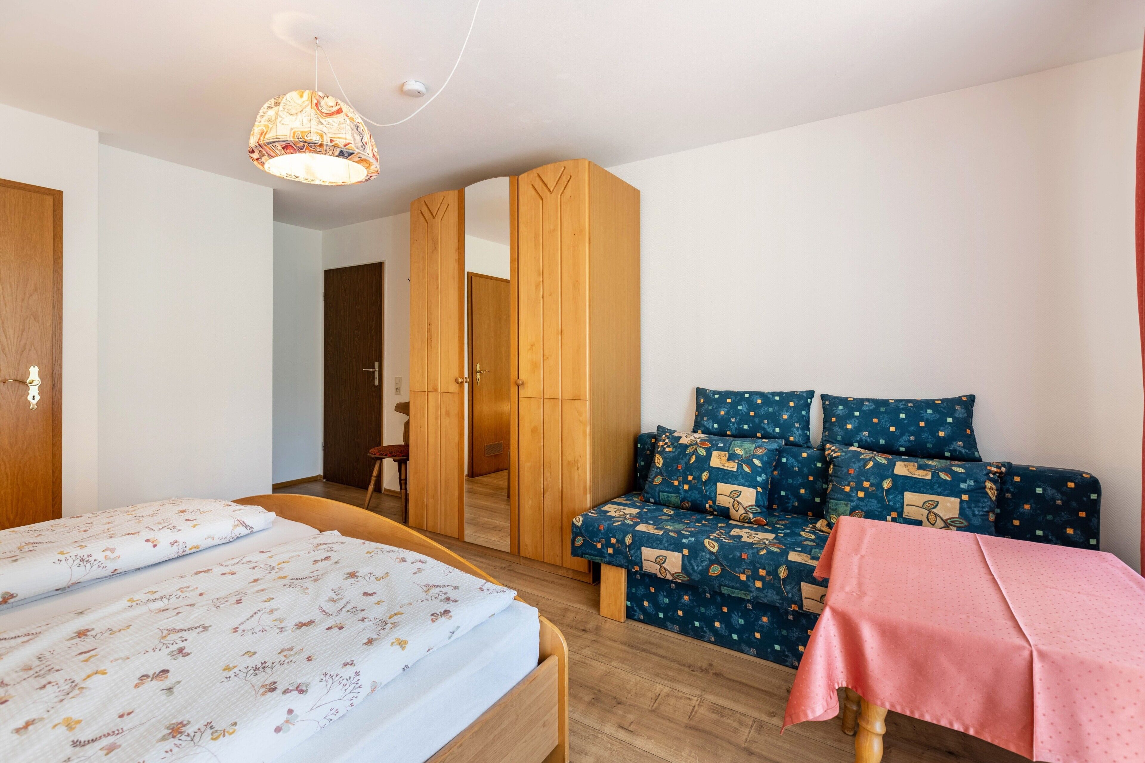 Un dormitorio con cama, sofá, mesa y armario.