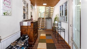 Un pasillo con techo de madera, un zapatero, un aparador, una escalera y una planta.