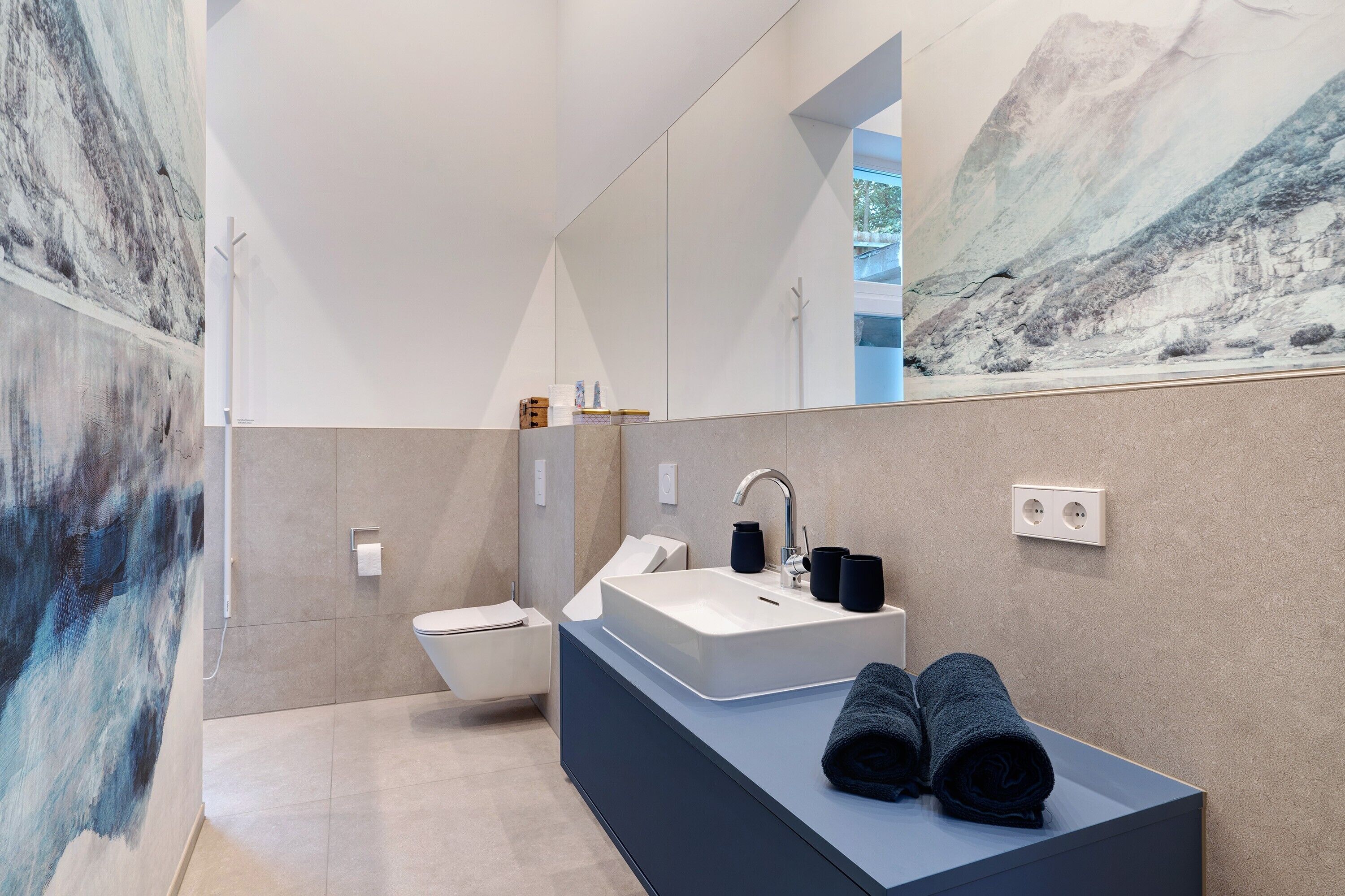 Un baño moderno con un espejo grande, un lavabo y un inodoro.
