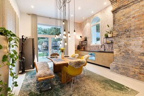 A modern kitchen with a brick wall, a dining area with yellow chairs, and a large window.