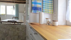 Eine Küche mit Steinwand, Holzarbeitsplatte und einem Essbereich mit Tisch und Stühlen.
