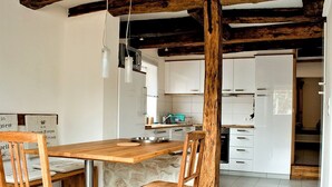 Eine moderne Küche mit einer Holzinsel, weißen Schränken und freiliegenden Holzbalken.