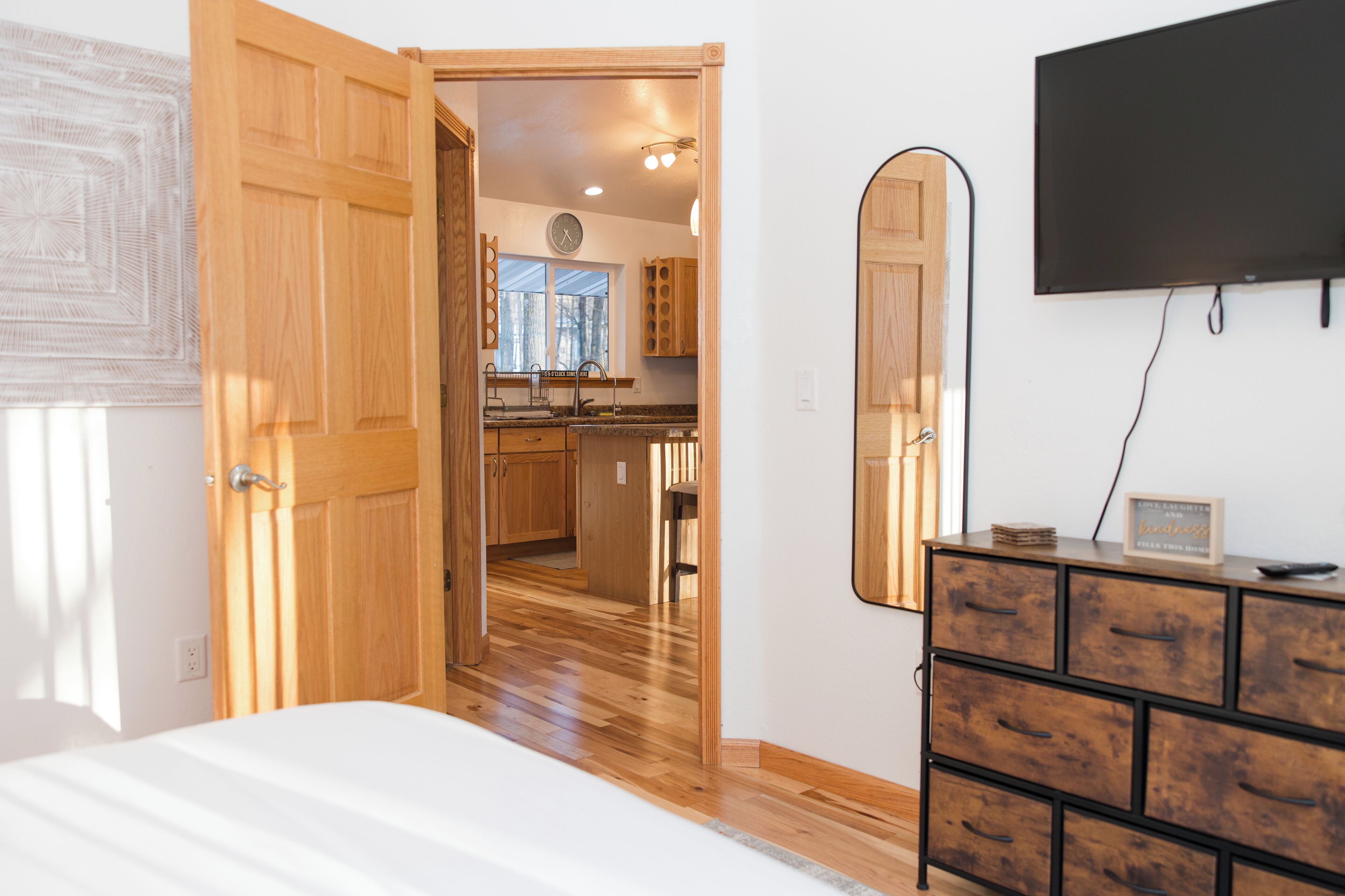 A bedroom with a wooden door, a dresser, and a TV mounted on the wall.