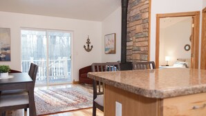 A kitchen with a granite countertop, wooden cabinets, and a stone accent wall. - The best patio and firepit at The Cat's Lair in the woods!  Level 2 EV charger! (Egg Harbor)