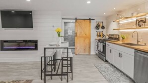 A modern kitchen with a flat-screen TV, a fireplace, and a sliding barn door.