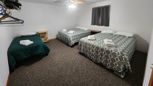 A room with two beds, a ceiling fan, a small table, and a hanging coat rack. - Lazy Fox Lodge, Lake of the Woods
 (Baudette)