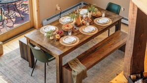 A wooden dining table set with plates, glasses, and a vase with greenery. - Hot Tub, Sauna, Game Room, Fire Pit, BBQ, Karaoke, Dogs OK (Bethel)