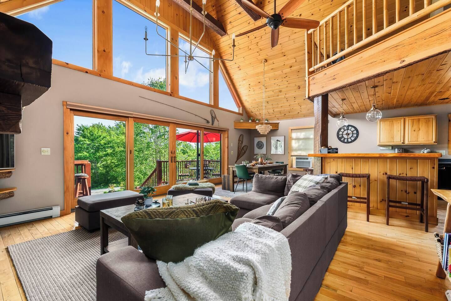A spacious living area with a large sofa, a dining table, and a kitchen area with wooden cabinets.