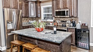 A modern kitchen with dark wood cabinets, stainless steel appliances, a granite countertop, and a built-in wine cooler. - Peaceful Pocono Home Hot Tub minutes away from Kalahari, Camelback, Mt Airy (Long Pond)