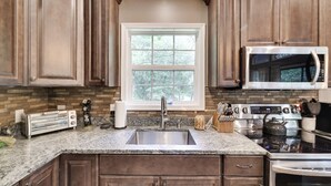 A kitchen with wooden cabinets, a stainless steel microwave, a toaster, a kettle, and a sink. - Peaceful Pocono Home Hot Tub minutes away from Kalahari, Camelback, Mt Airy (Long Pond)