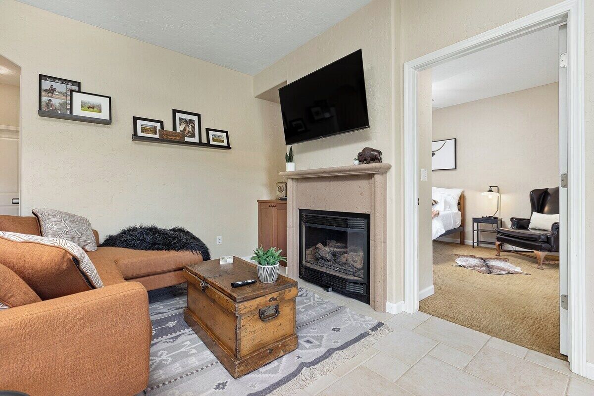 A living room with a fireplace, a television mounted above it, and a sofa.