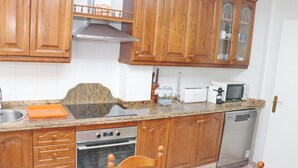 Una cocina con armarios de madera, microondas, tostadora y lavavajillas.