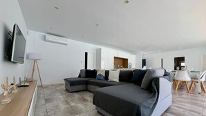 A modern living room with a sectional sofa, a flat-screen TV, and a dining area with a table and chairs. - El Azul House in Chiclana (Chiclana)