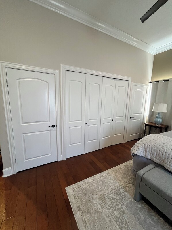 A bedroom with a bed, a nightstand, a lamp, a dresser, and a mirror.