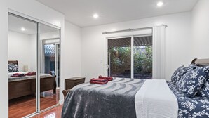 A bedroom with a bed, a desk, and a sliding glass door leading to a balcony. - Convenient Modern COZY 4BA/2BR Hidden GEM (Milpitas)