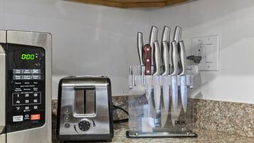A kitchen with a digital clock, a toaster, and a knife block.