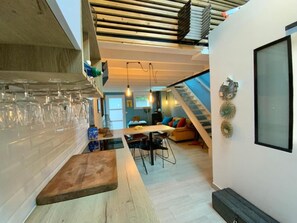 A modern kitchen with a wooden countertop, a dining area with a table and chairs, and a staircase leading to an upper level.