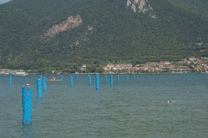 A lake with blue posts, a swimmer, and a town with buildings on a hillside. - Interno 2 in Iseo With 1 Bedrooms and 1 Bathrooms (Iseo)